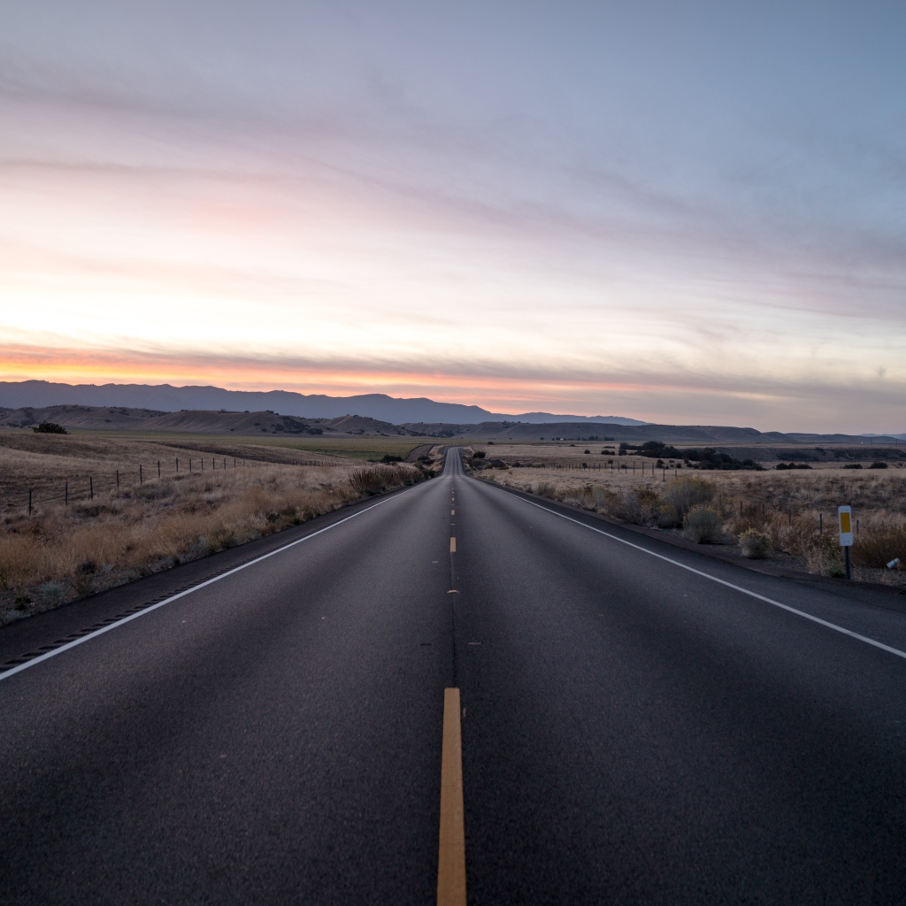 Асфальтная дорога уходит вдаль на фоне неба