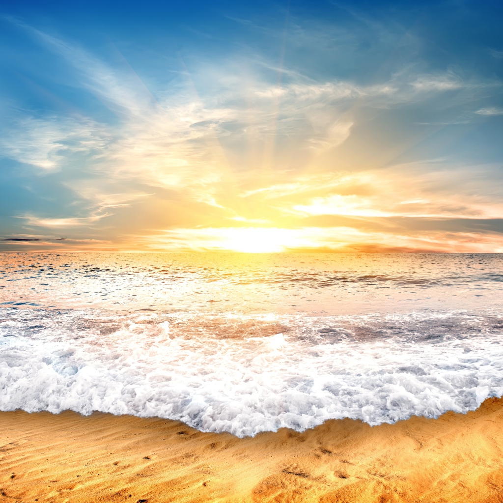 Белые волны на желтом песке на закате солнца 