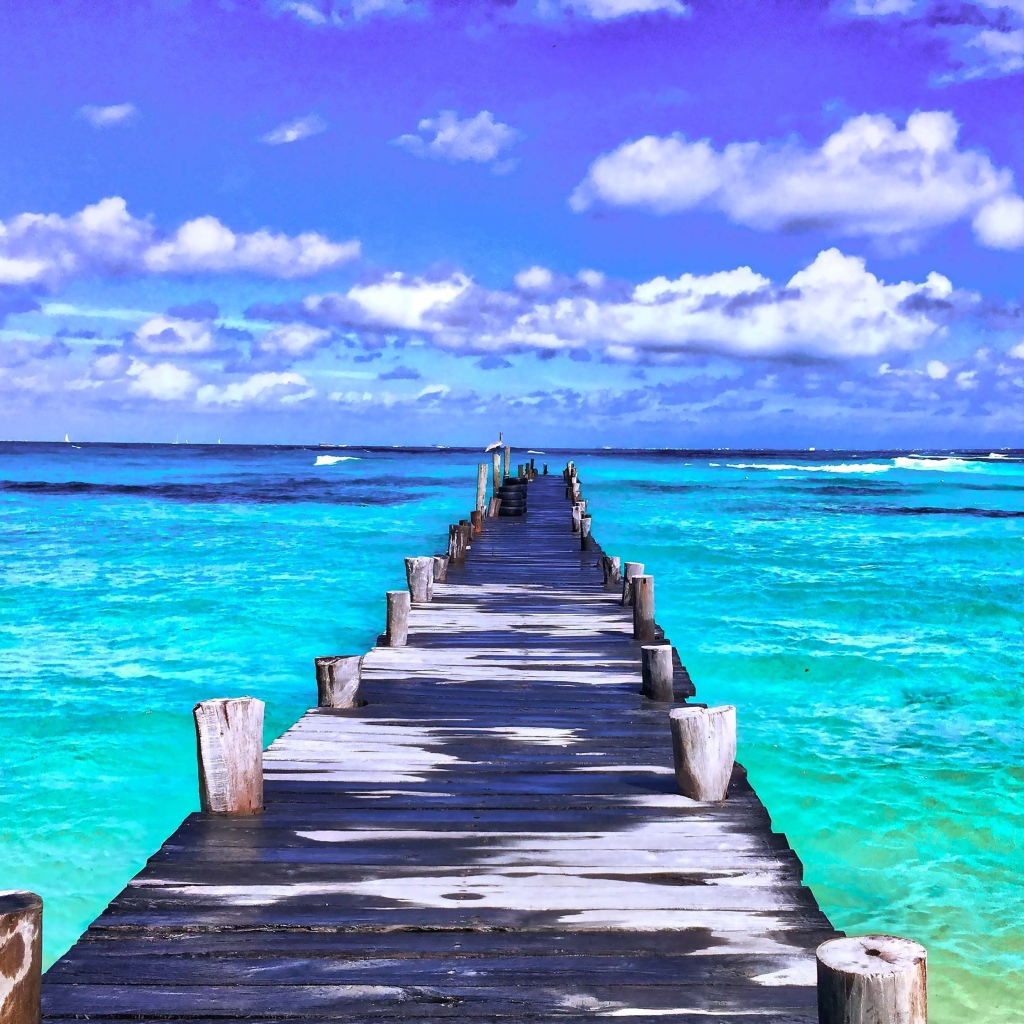 Деревянный мокрый пирс в голубом океане под красивым небом