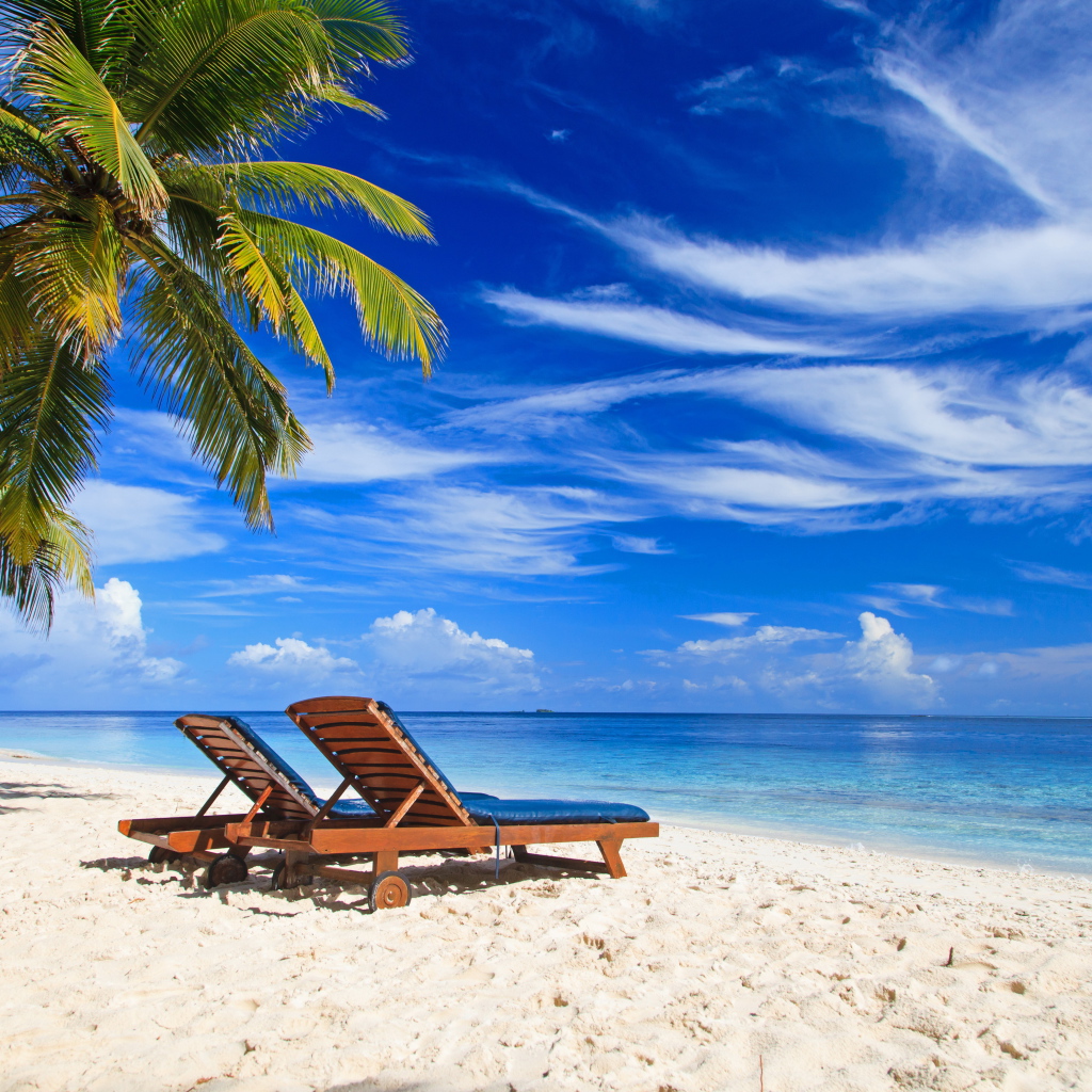 Шезлонги на тропическом пляже под голубым небом