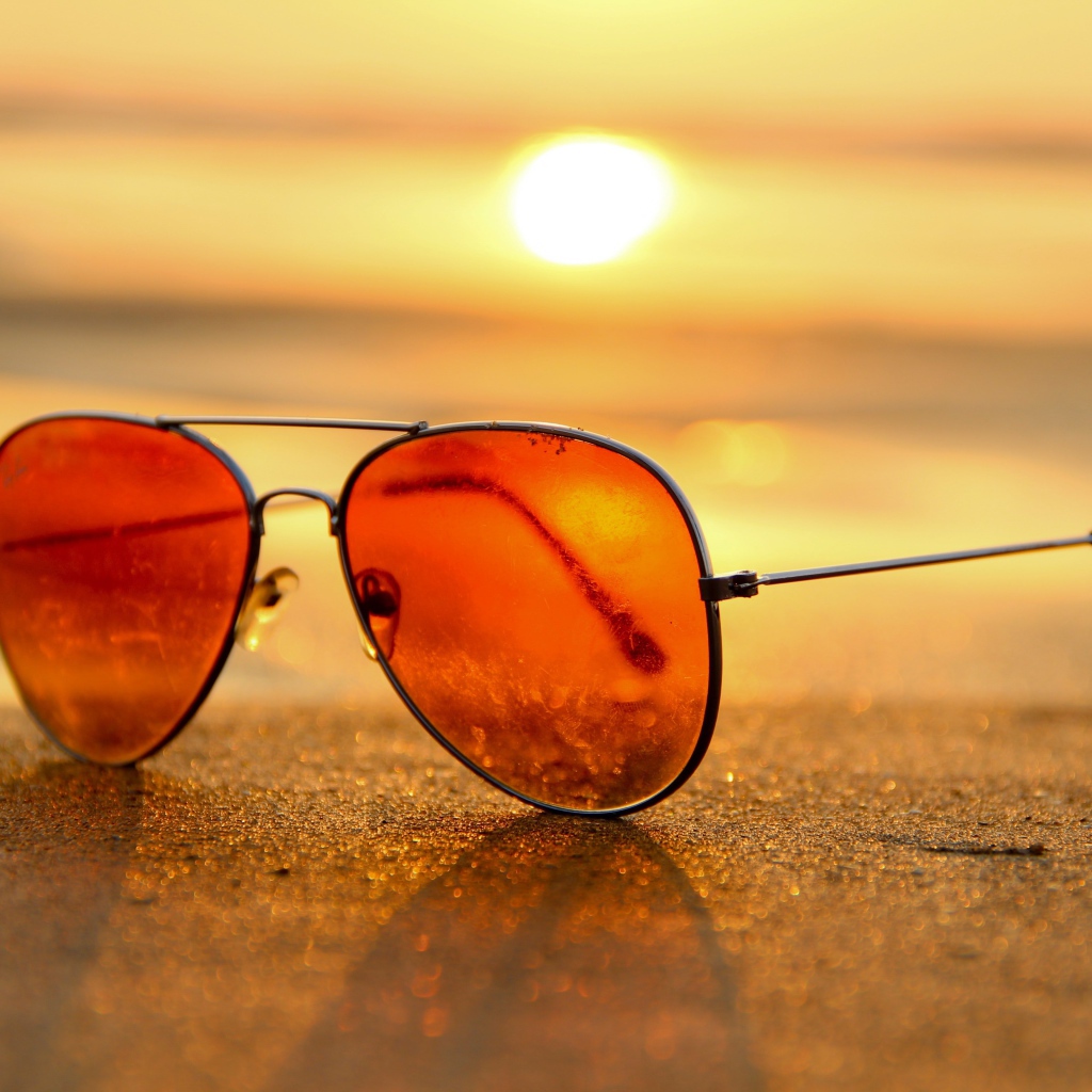 Солнечные очки лежат на горячем морском песке