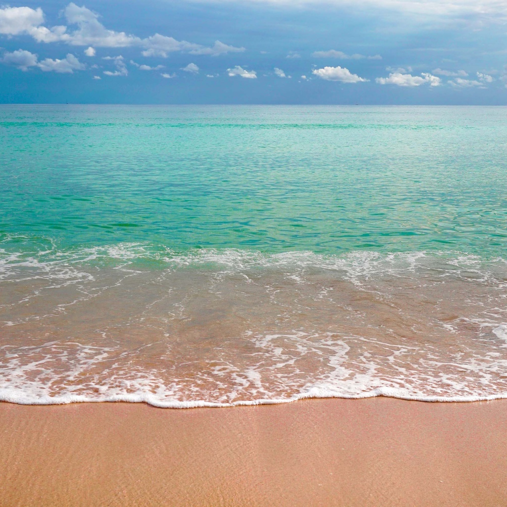 Волны голубого океана на желтом песке под голубым небом