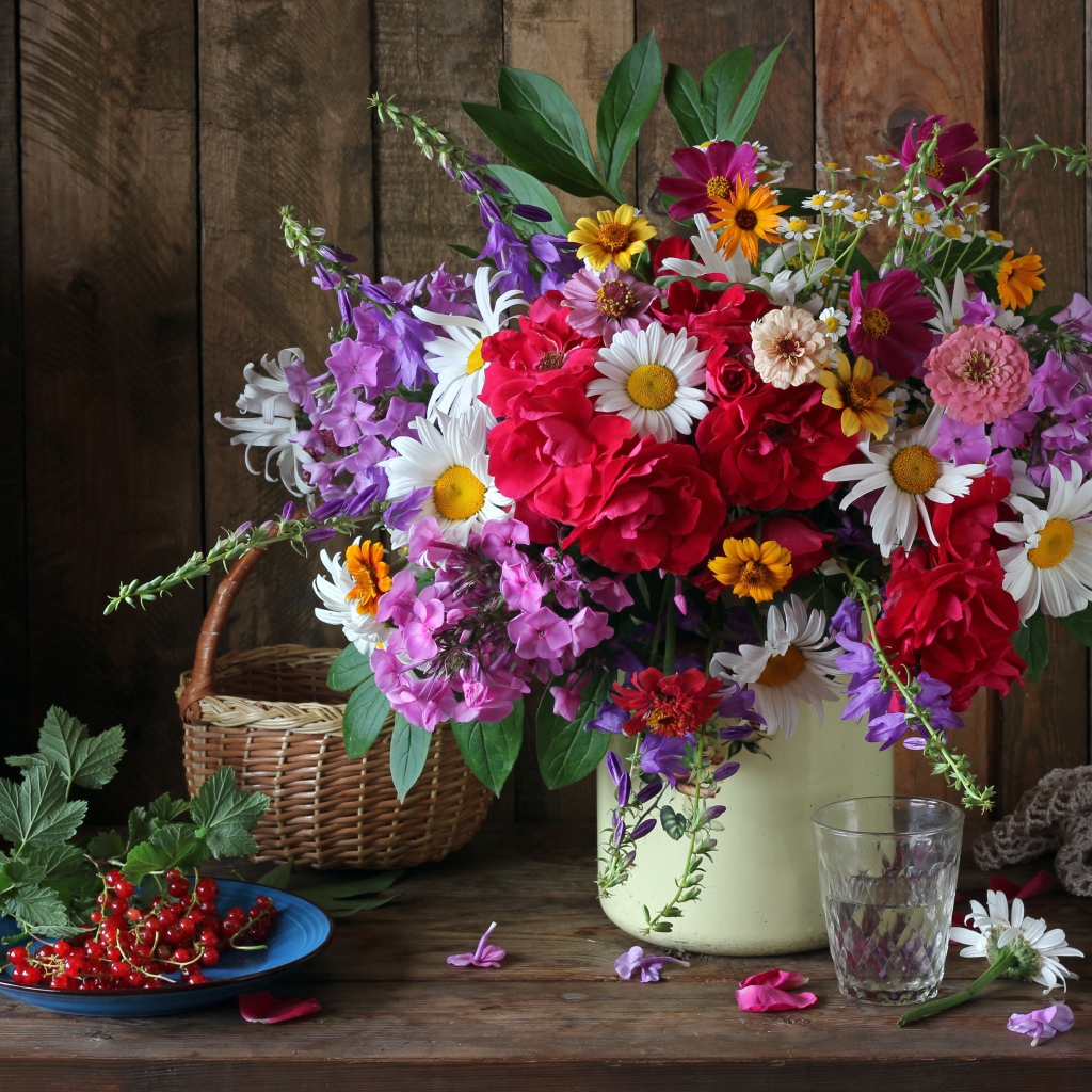 Красивый букет стоит на  столе с красной смородиной