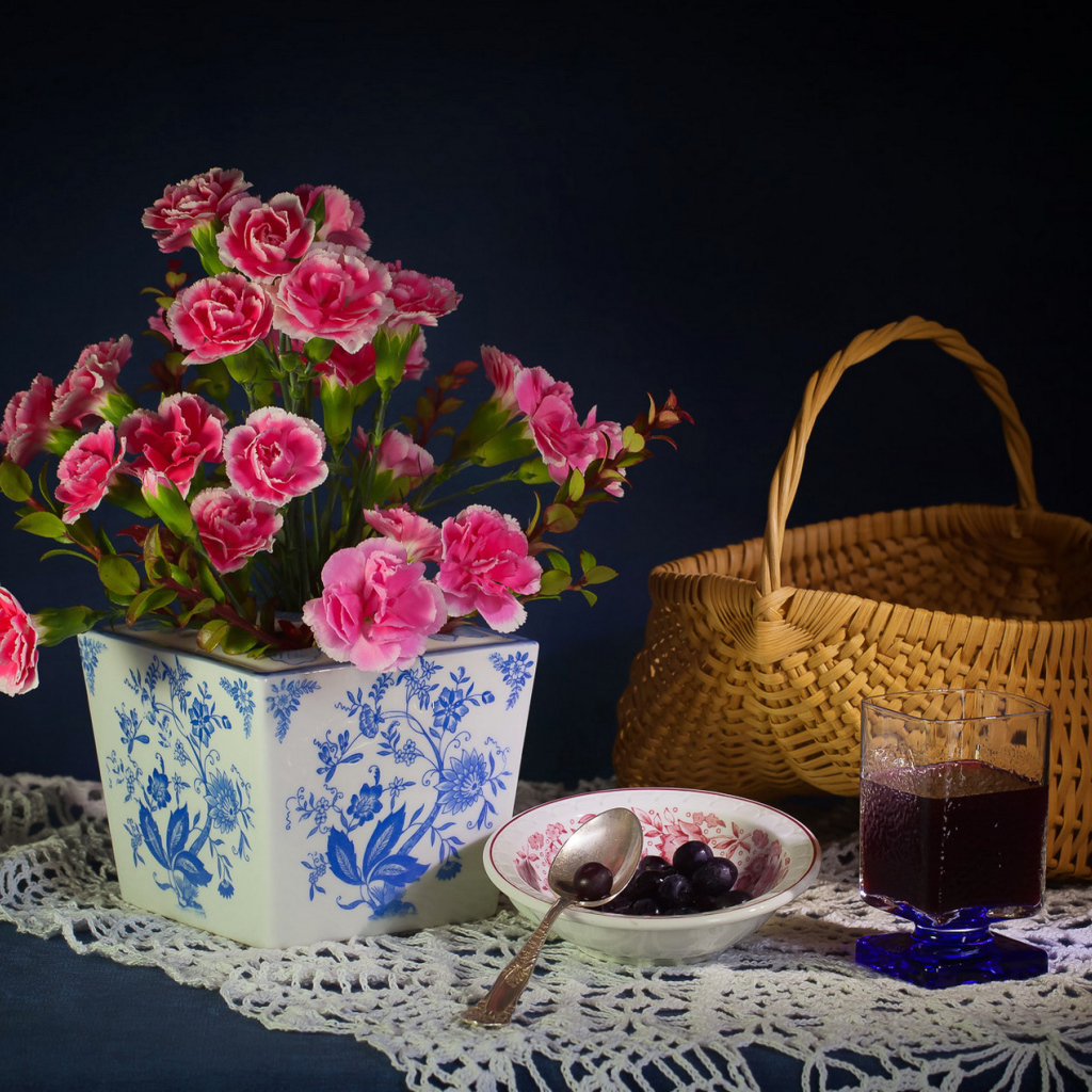 Букет гвоздик в красивой вазе на столе с корзиной и соком