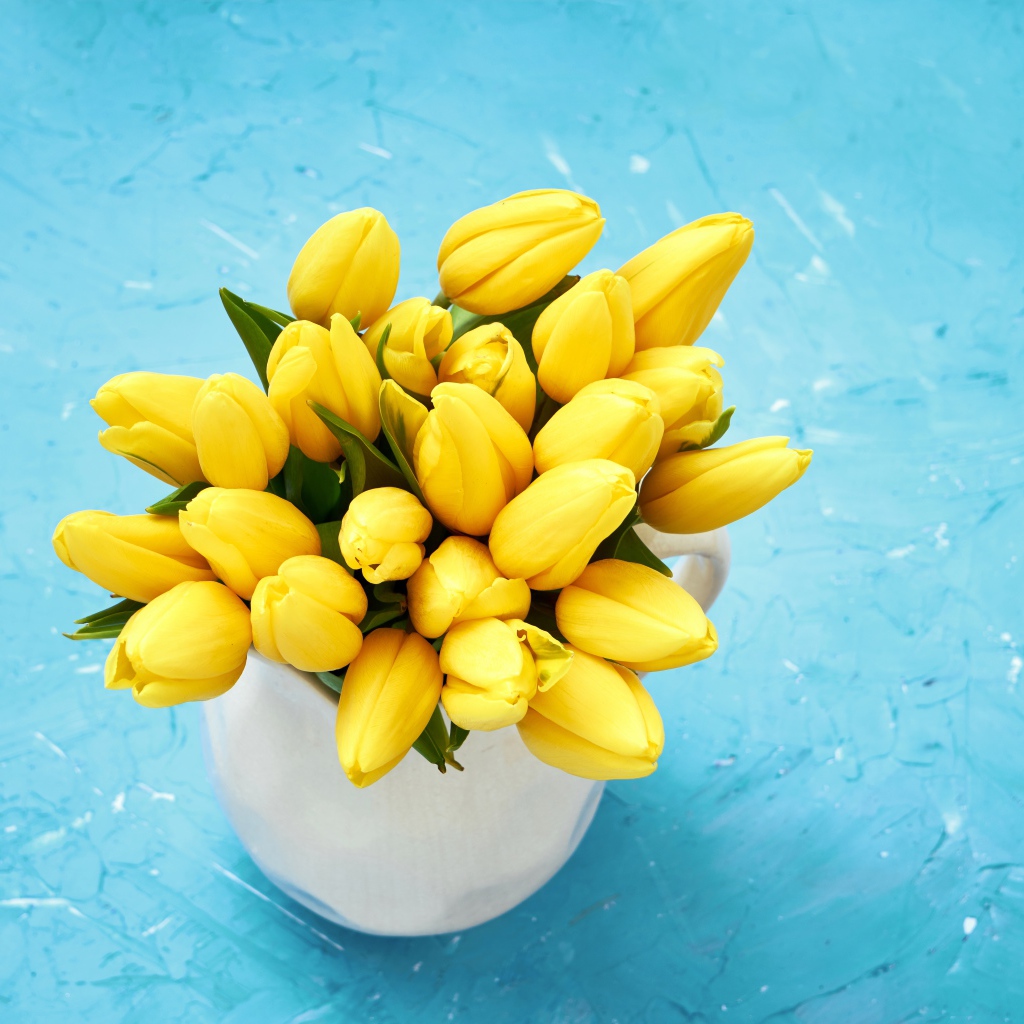 Букет оранжевых тюльпанов в белой вазе на голубом фоне