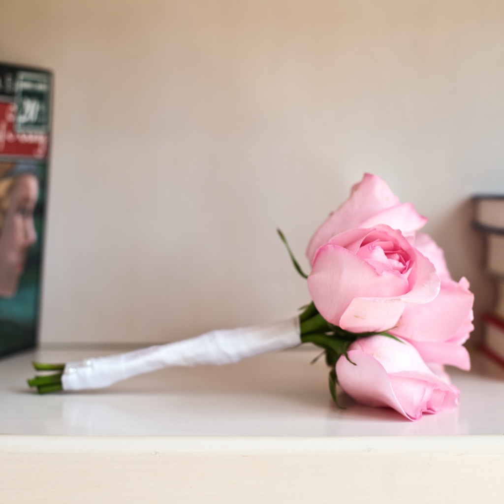 Букет розовых роз лежит на полке с книгами