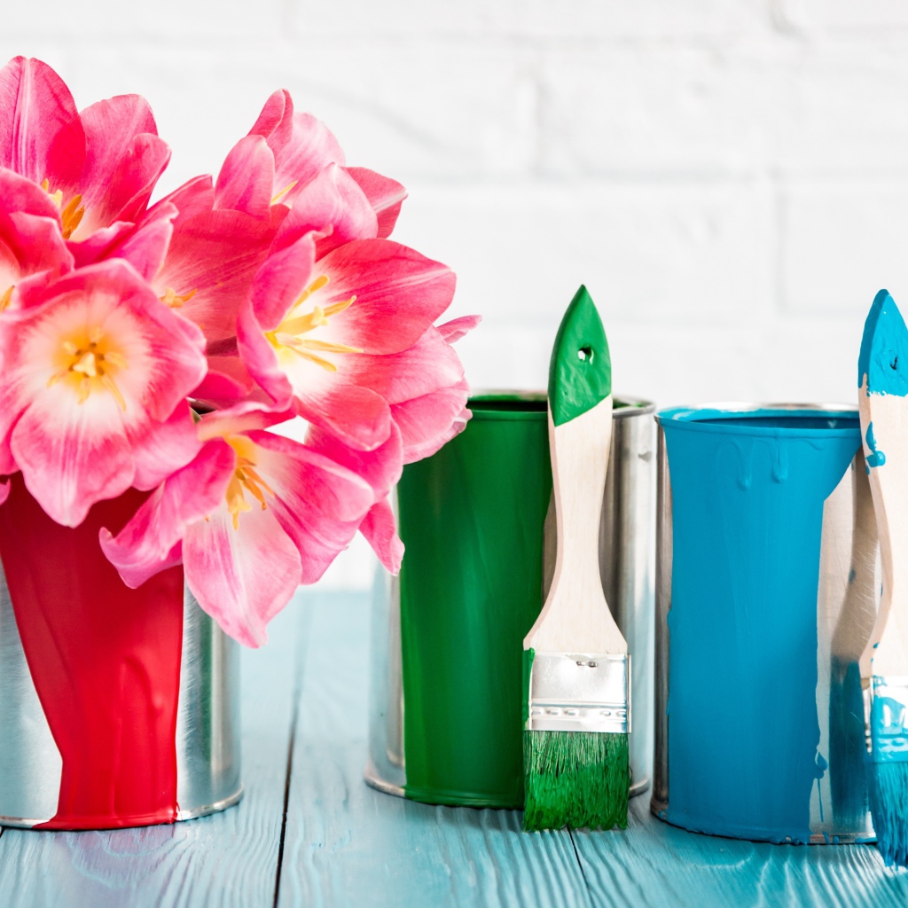 Букет розовых тюльпанов на столе с банками краски и кисточками