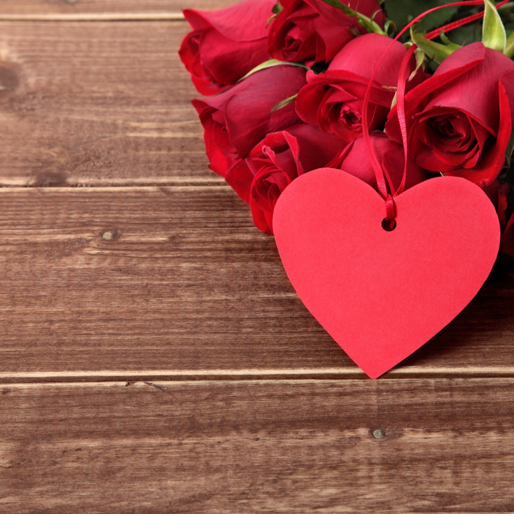 Букет красных роз на деревянном столе с красным сердцем