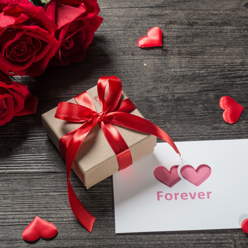Букет красных роз с подарком и открыткой на столе