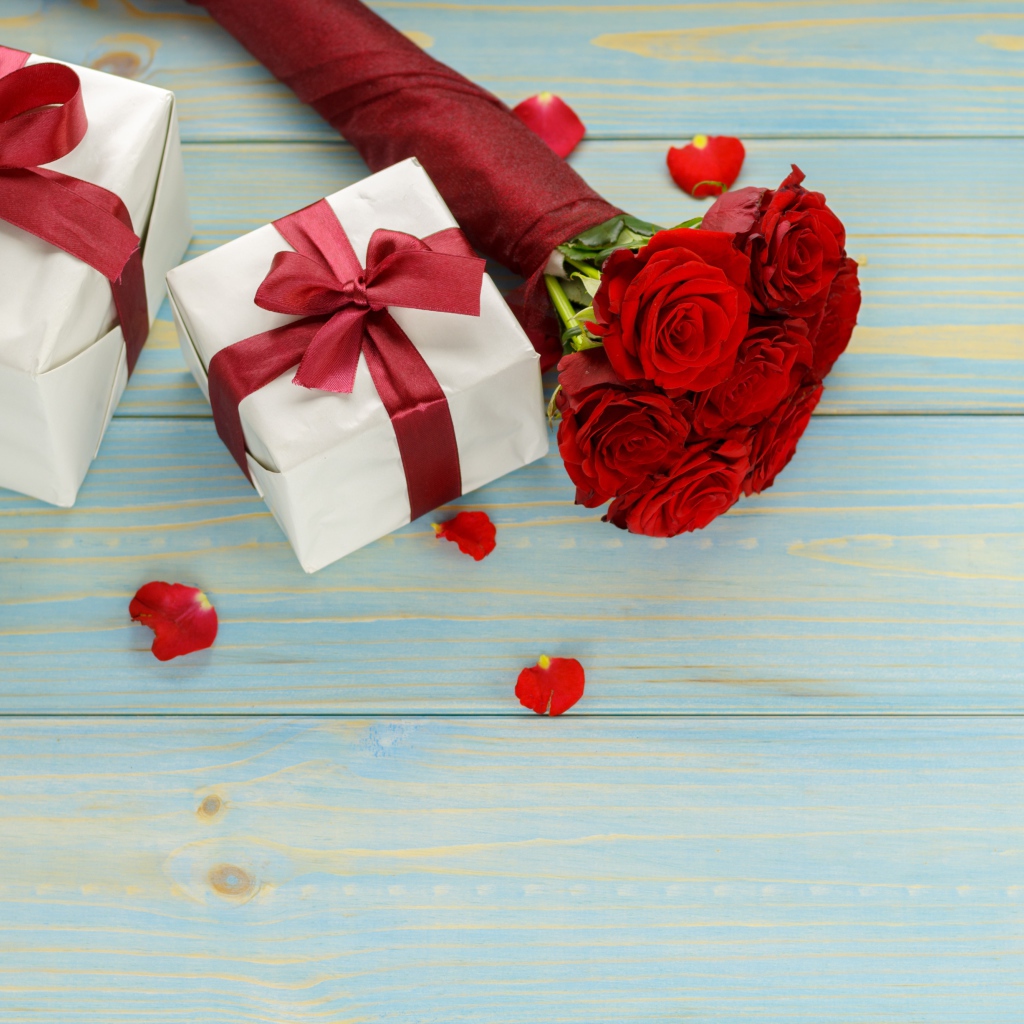 Букет красных роз с подарками на столе