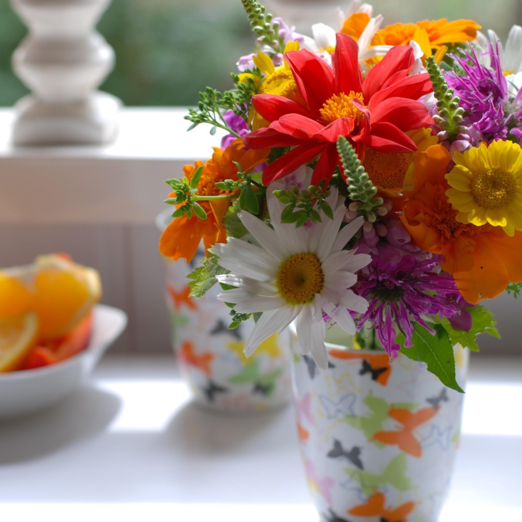 Букет разноцветных  садовых цветов в вазе на столе 