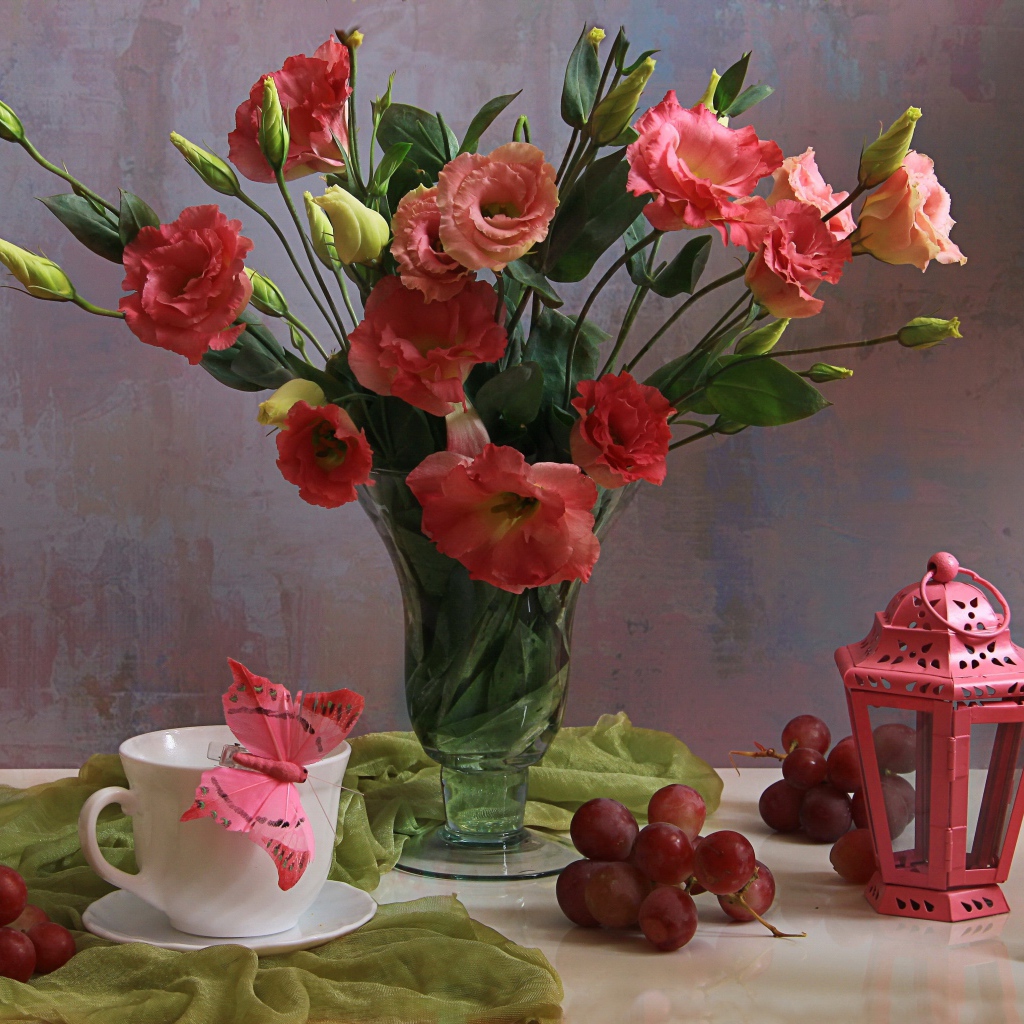 Букет розовых цветов эустомы на столе с виноградом