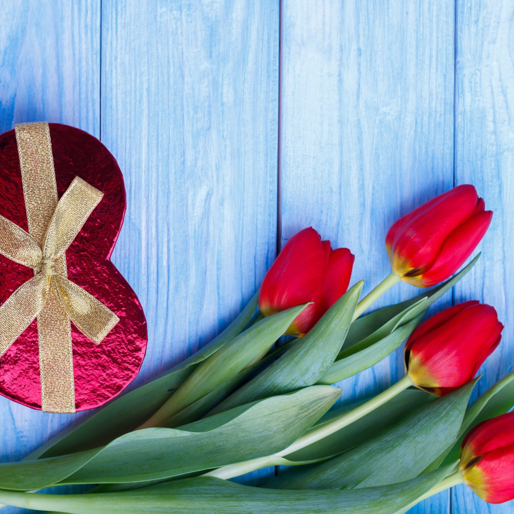Букет красных тюльпанов на синем фоне с подарком в форме сердца