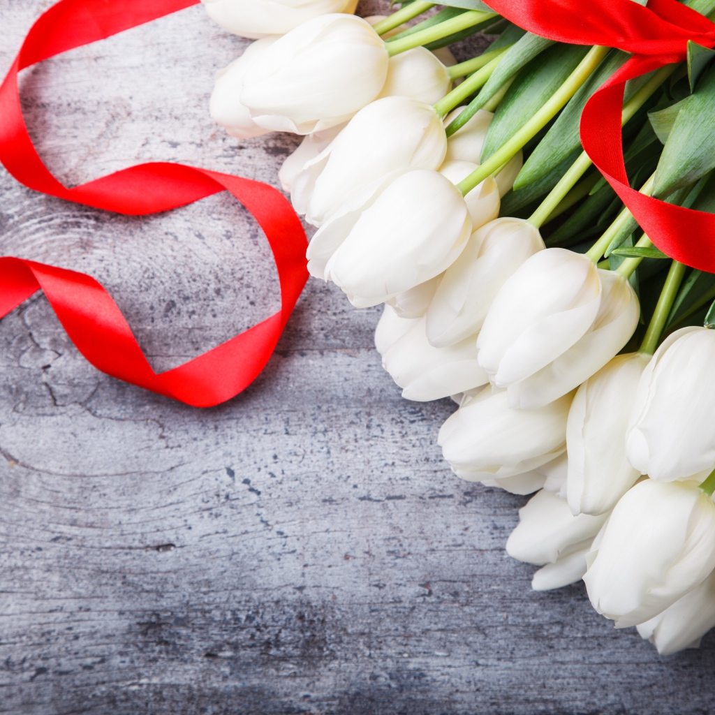 Букет белых тюльпанов с красным бантом на сером столе