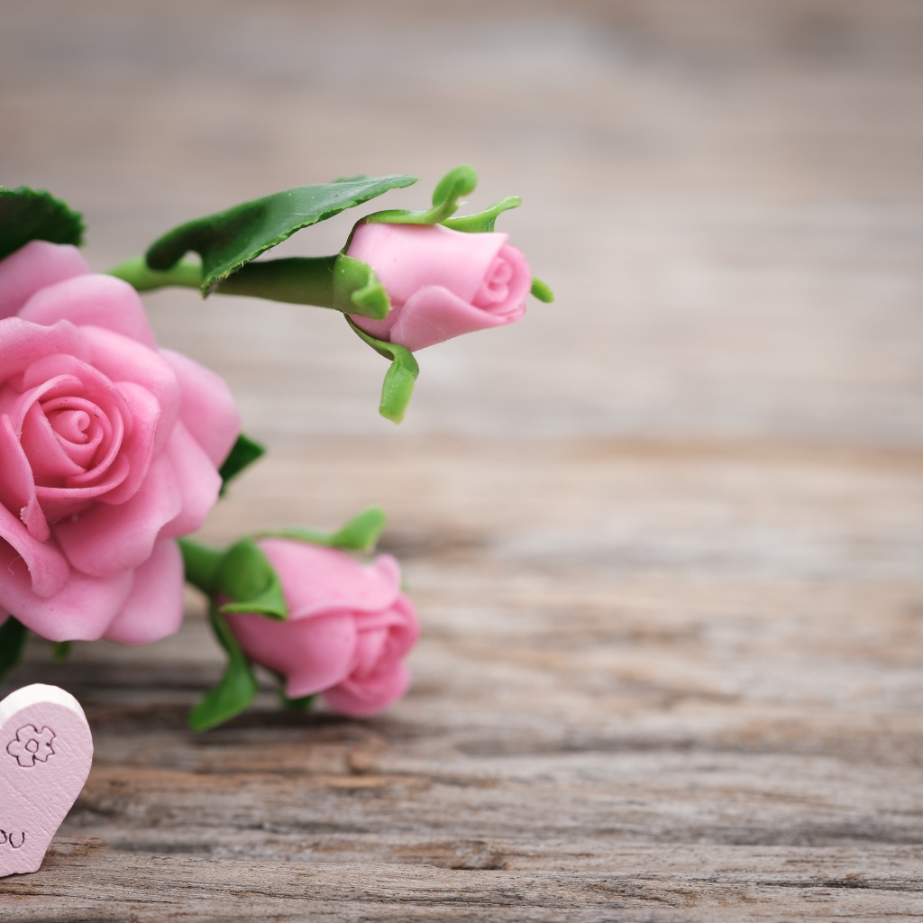 Розовые искусственные розы с сердцем на деревянном фоне
