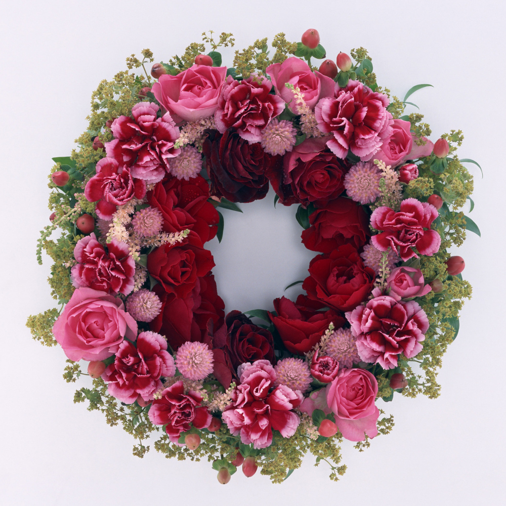 Венок и красных роз с цветами гвоздики на сером фоне