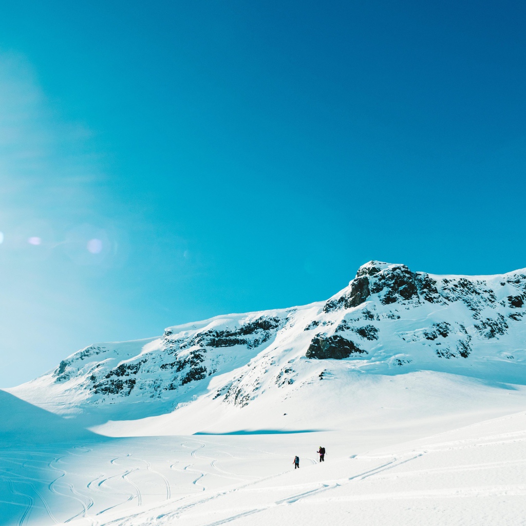 Красивые заснеженные горы под голубым небом в лучах солнца 