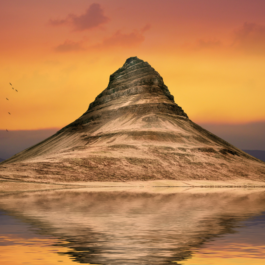 Гора отражается в воде на фоне неба на закате