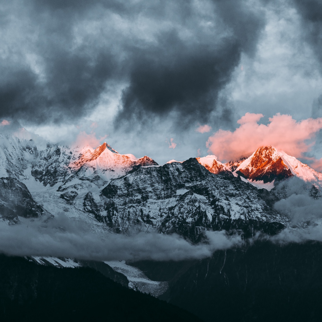 Солнце на рассвете освещает вершины заснеженных гор 