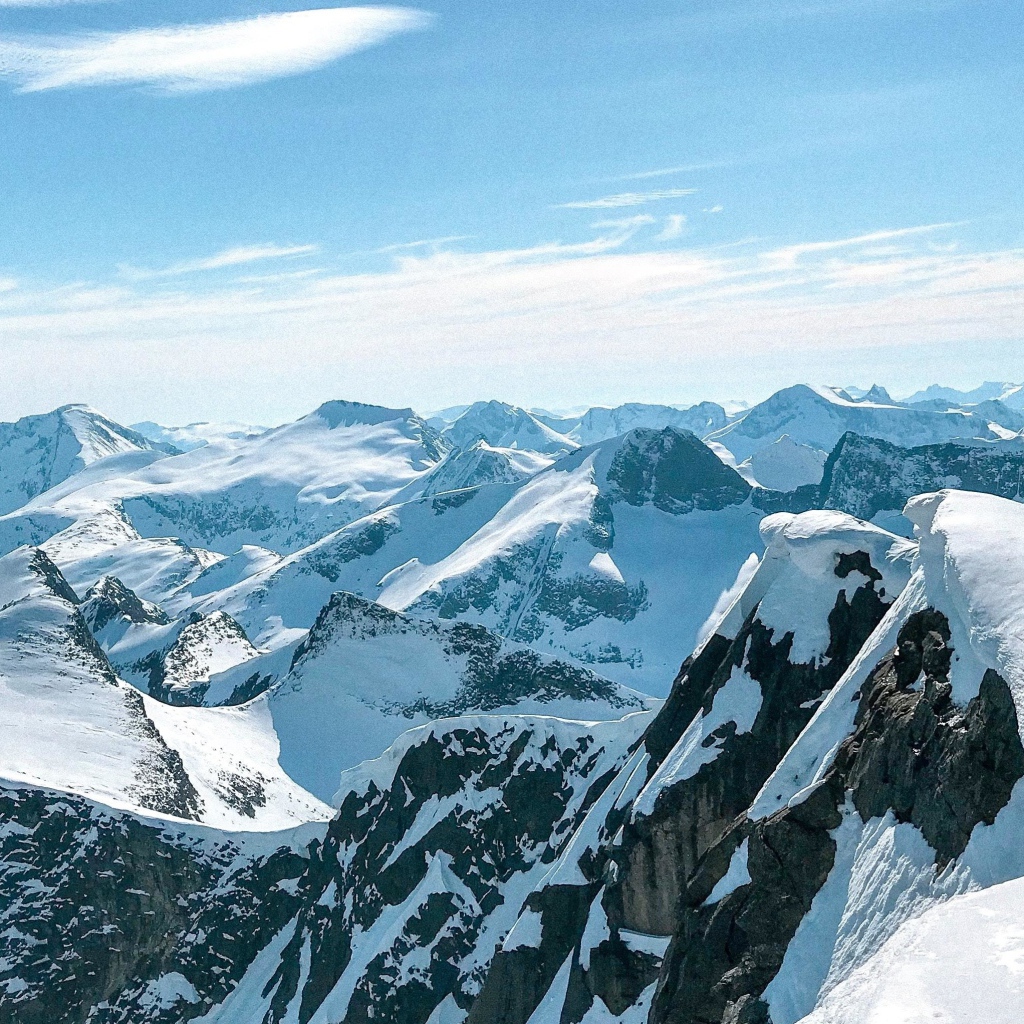 Верхушки заснеженных гор в лучах солнца под голубым небом 