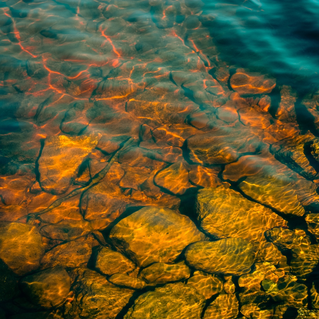 Камни на дне озера с чистой водой в лучах солнца
