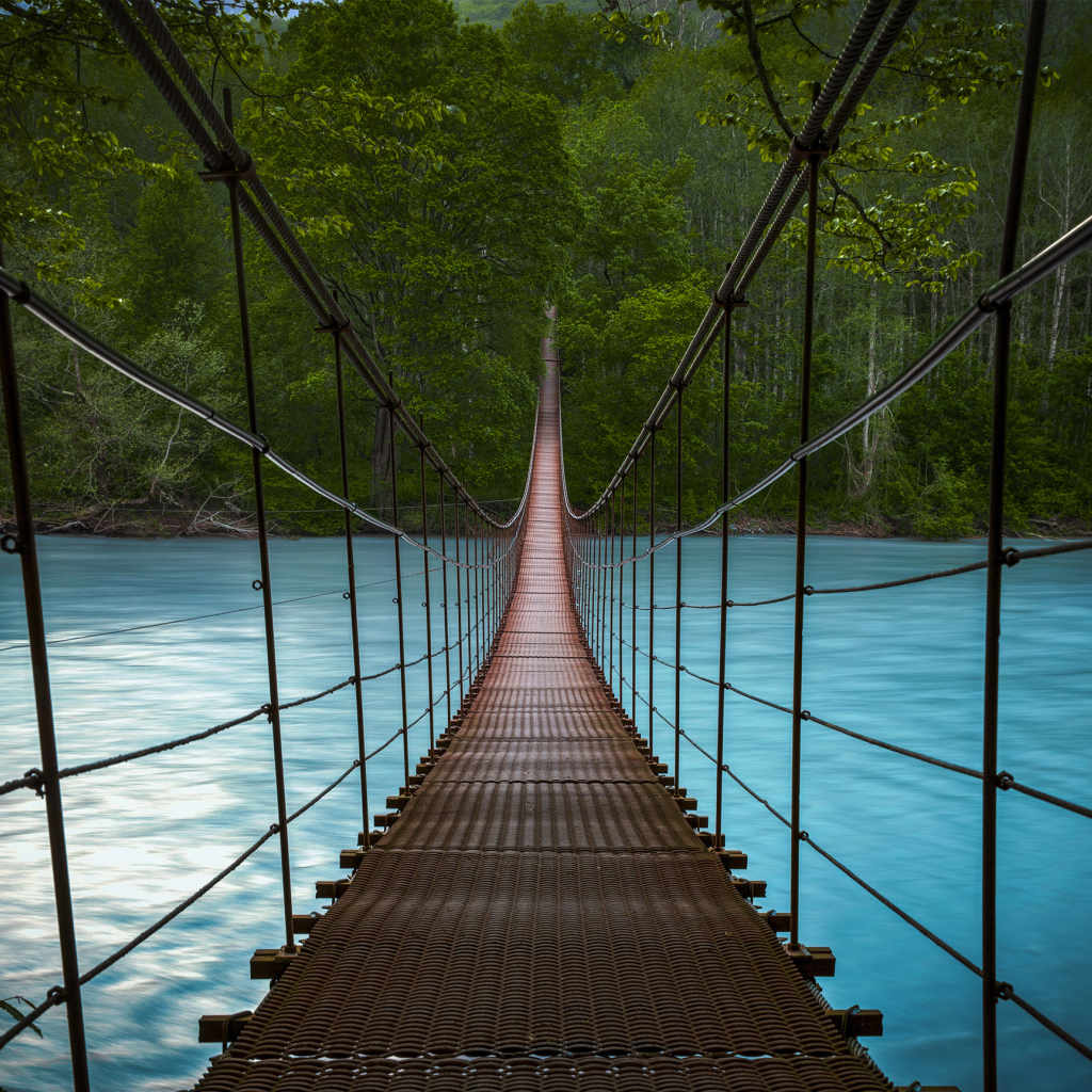 Подвесной мост над быстрой рекой с голубой водой