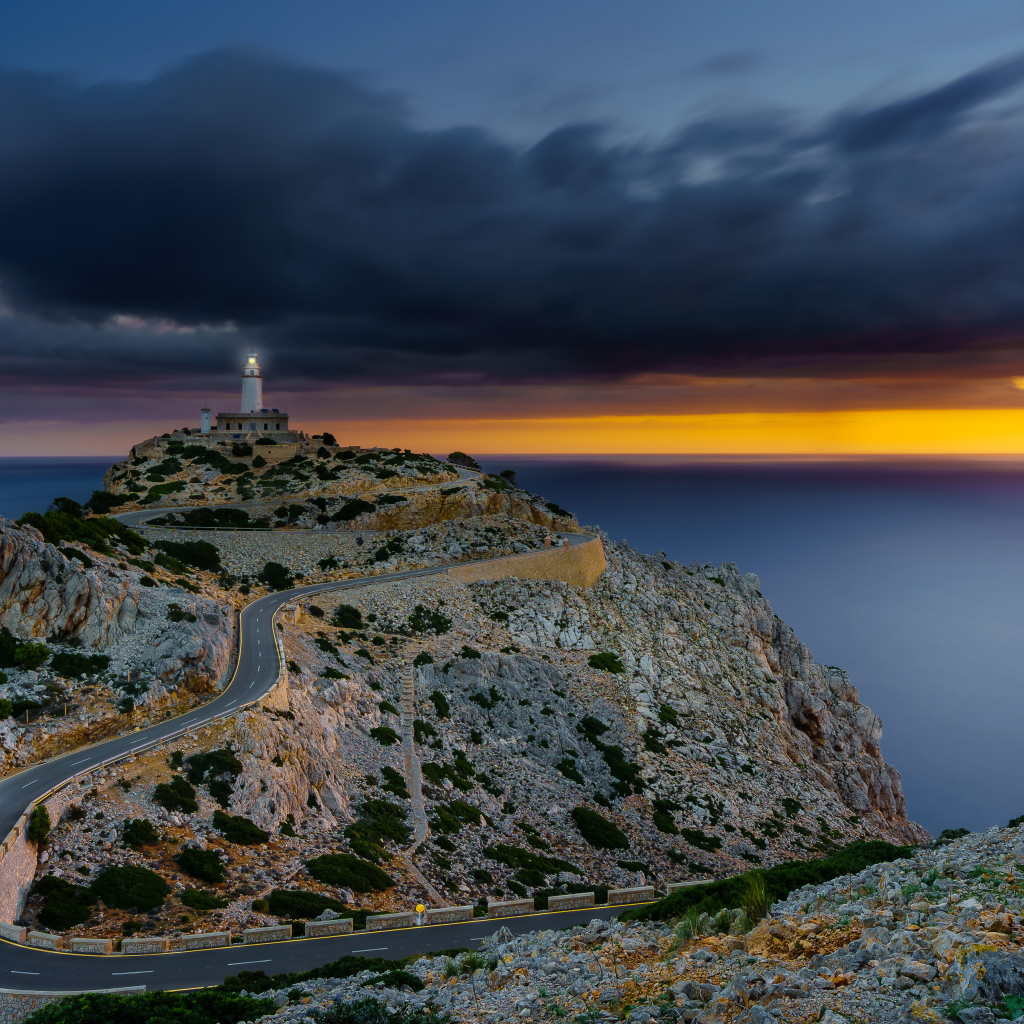 Извилистая дорога ведет к маяку на краю скалы под пасмурным небом