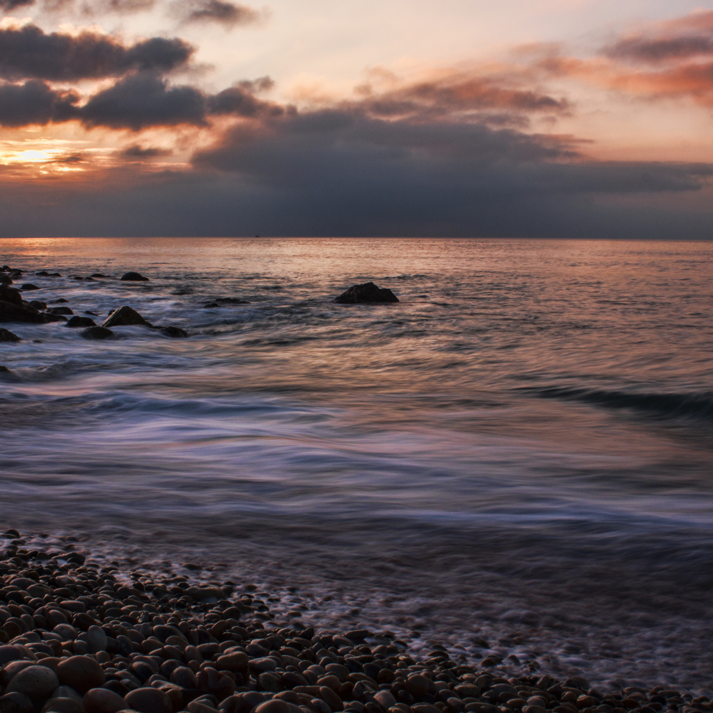 Мелкие камни на берегу моря на закате