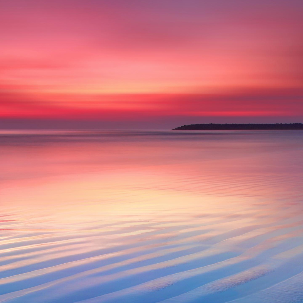 Мокрый белый песок на берегу океана на закате