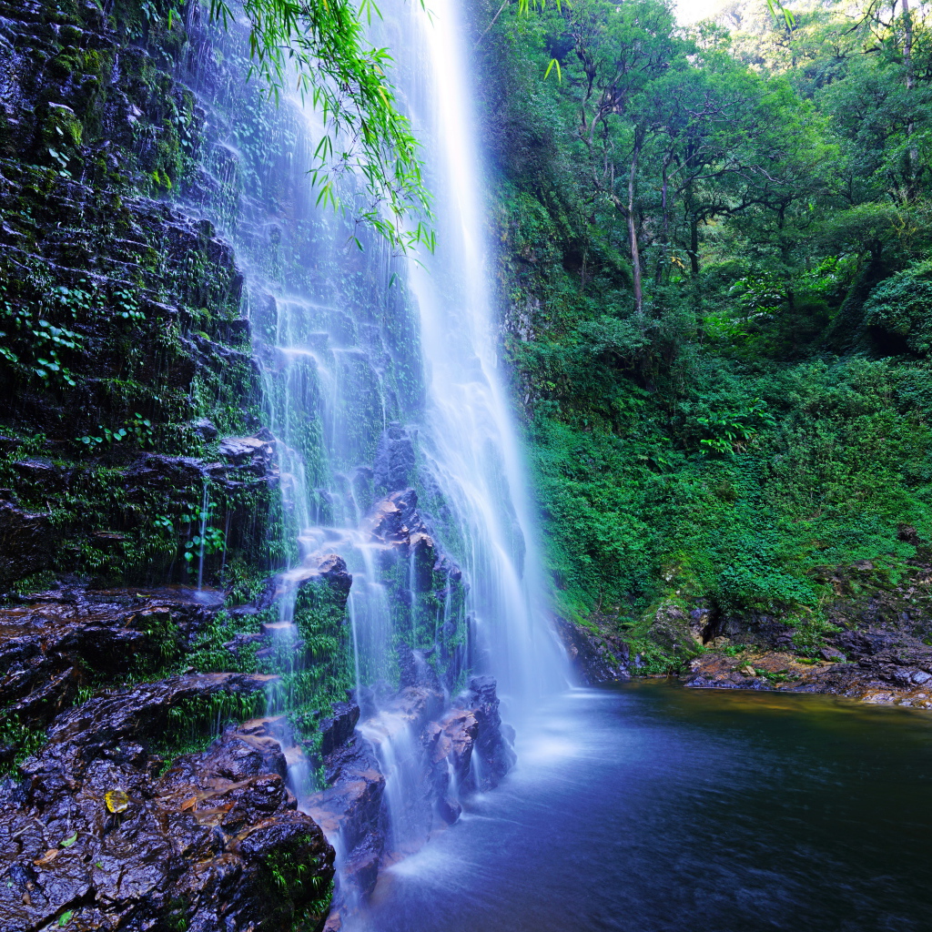 Быстрый водопад стекает по мокрым камням со скалы