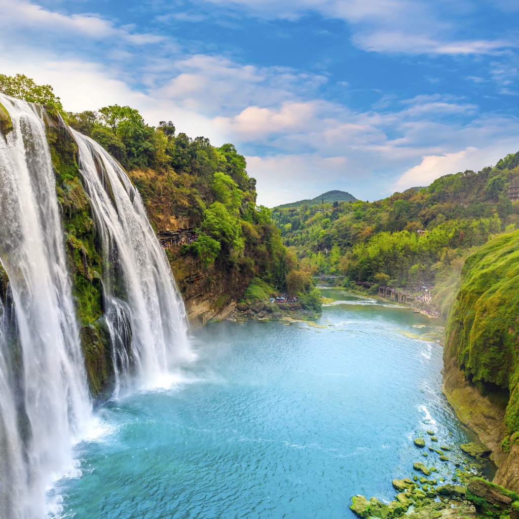 Быстрый водопад стекает с зеленых гор в реку