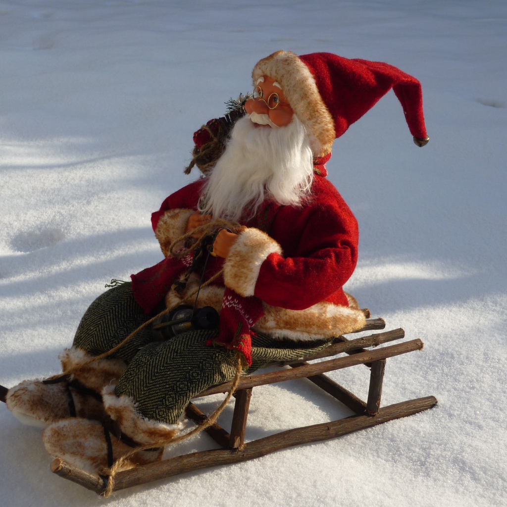 Игрушка деда Мороза на санках стоит на снегу