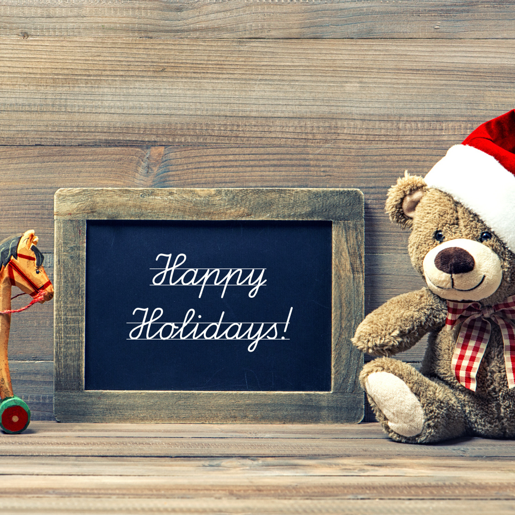 Игрушечный медвежонок Тедди в новогоднем колпаке на деревянном фоне с рамкой