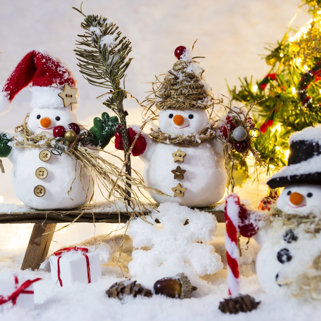 Три снеговика на снегу у искусственной елки на Новый год 