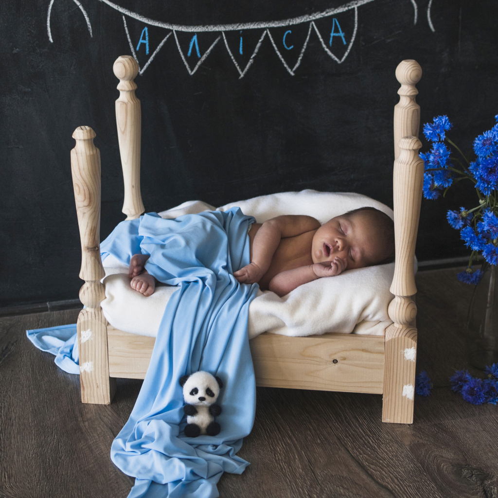 Грудной ребенок спит на деревянной кровати