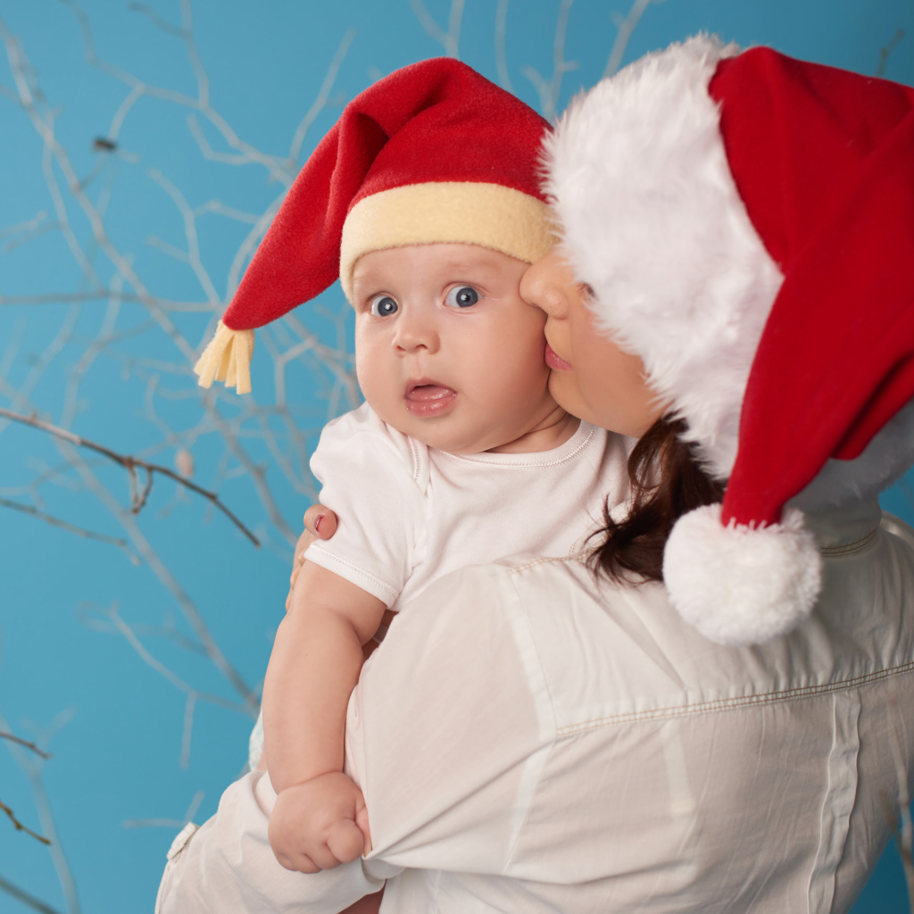 Маленький ребенок в новогоднем костюме на руках у мамы