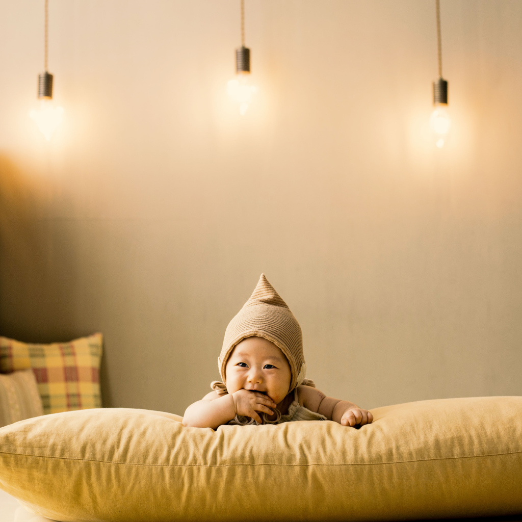 Маленький ребенок лежит на подушке под лампами