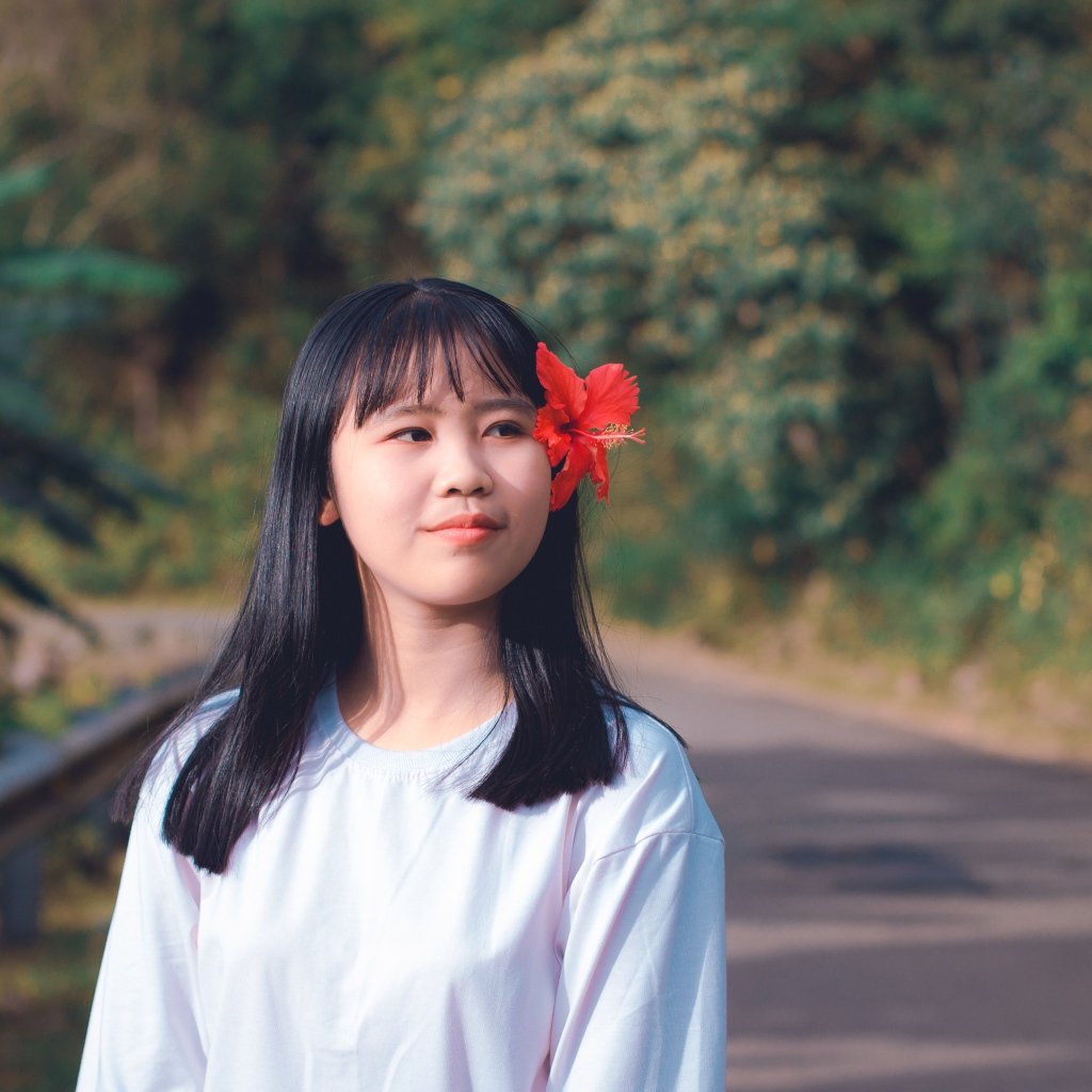 Девушка азиатка с красным цветком гибискуса в волосах