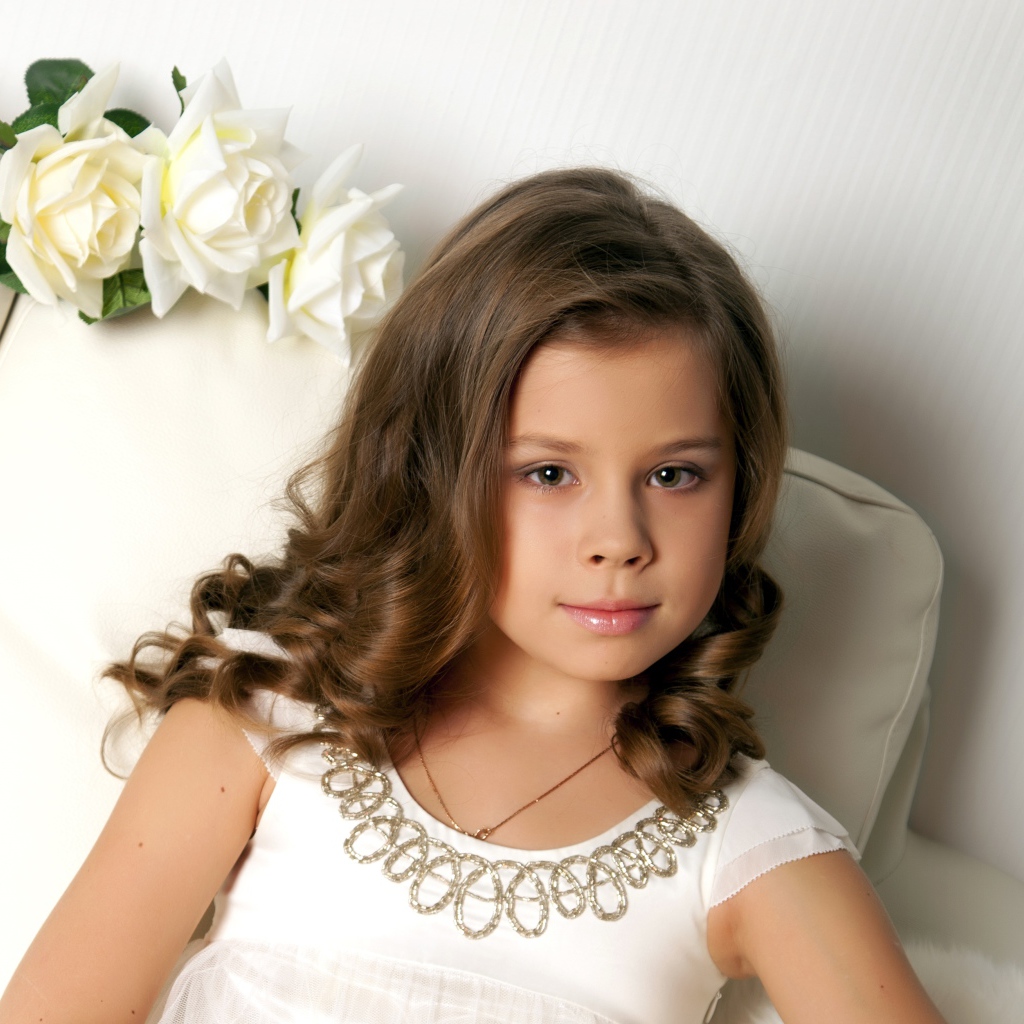 Красивая маленькая девочка сидит в кресле