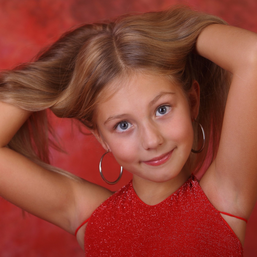 Красивая маленькая девочка с руками в волосах