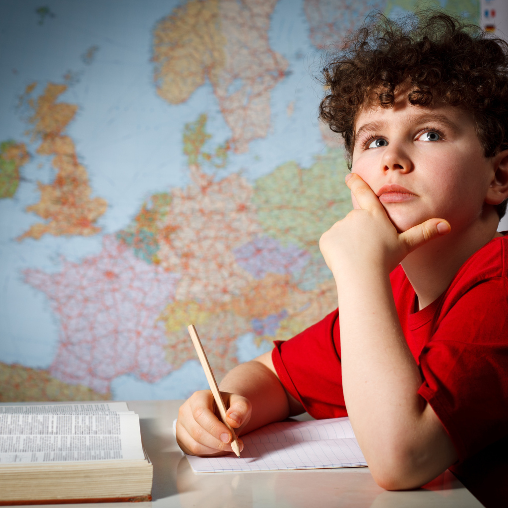 Мальчик ученик делает уроки за столом 