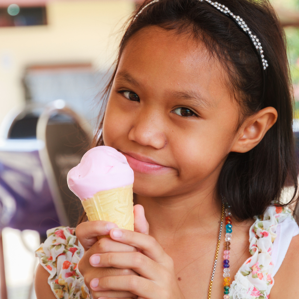 Маленькая девочка азиатка с мороженым в руке
