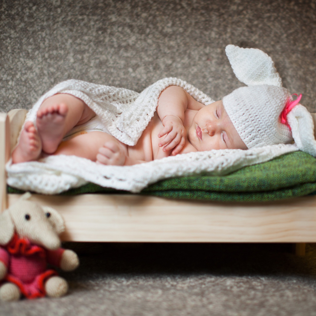 Маленький ребенок в костюме зайца на кровати 