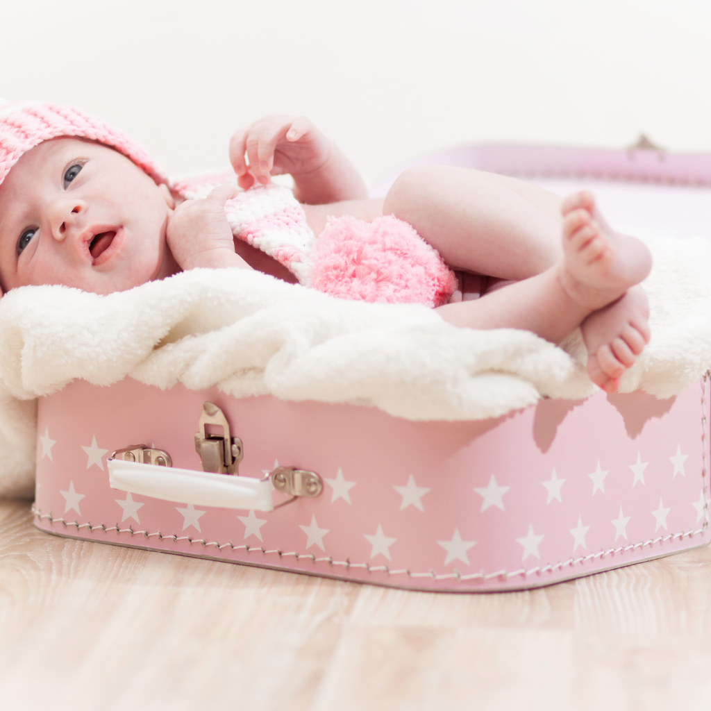 Маленький грудной ребенок спит в розовом чемодане