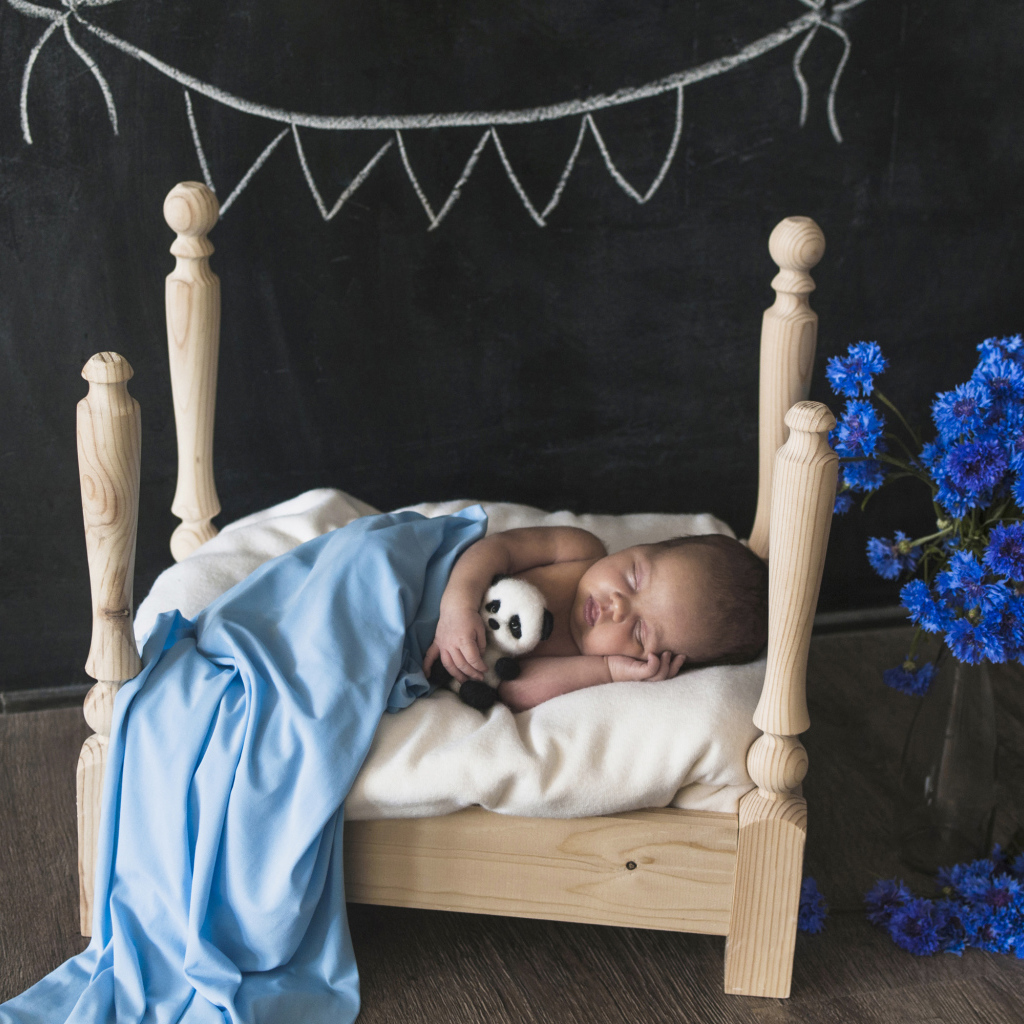 Маленький ребенок спит в деревянной кровати 