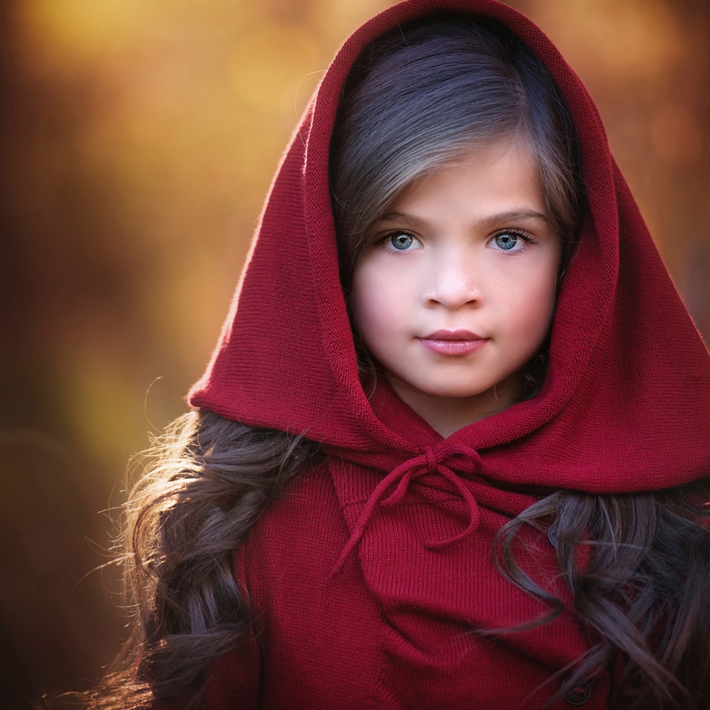 Маленькая красивая голубоглазая девочка с красным капюшоном на голове