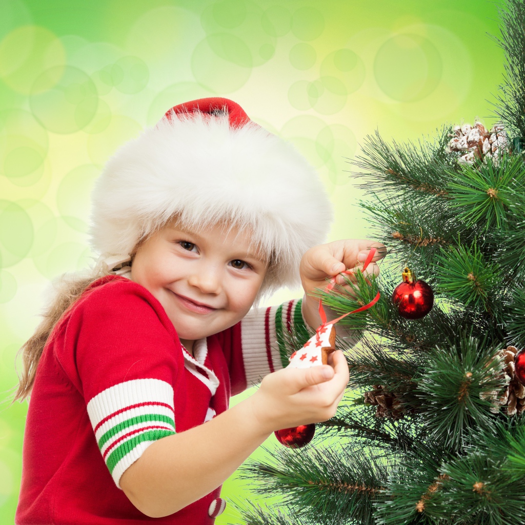 Маленькая красивая девочка наряжает елку на новый год