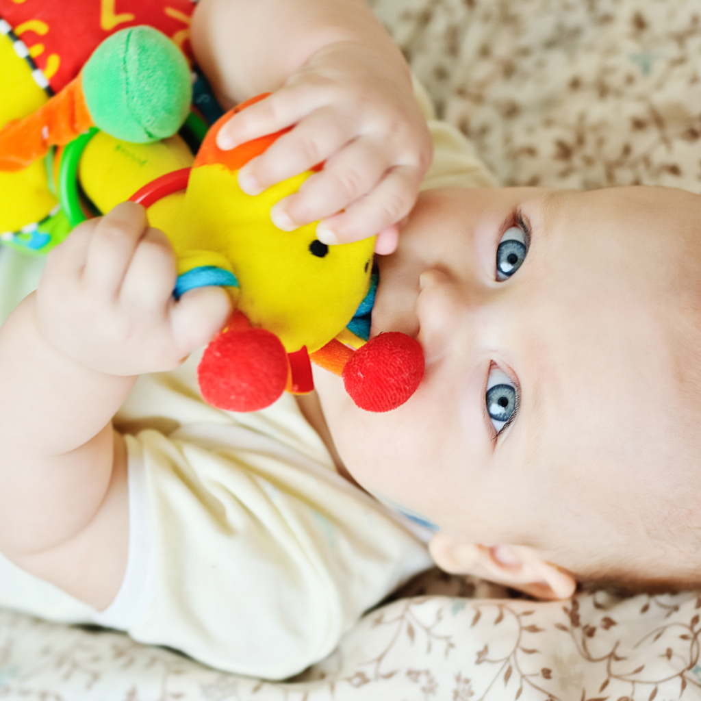 Маленький голубоглазый ребенок грызет игрушку