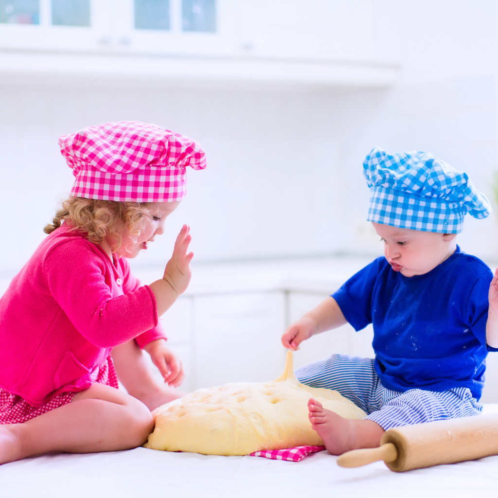 Маленькие мальчик и девочка на кухне с тестом