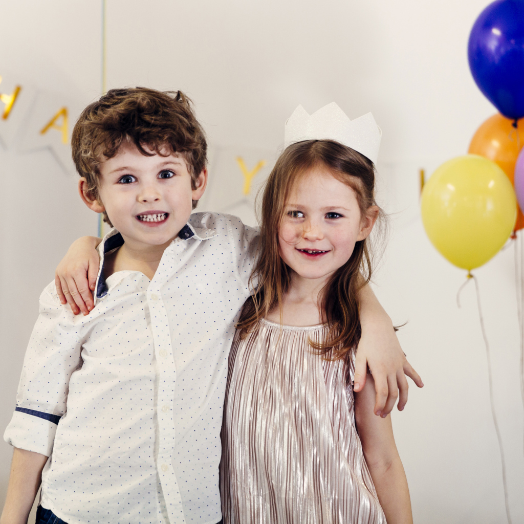 Маленькие мальчик и девочка на празднике с воздушными шарами